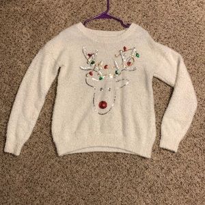 This is a fuzzy Christmas reindeer sweater. It is white, size M in kids (7-9).